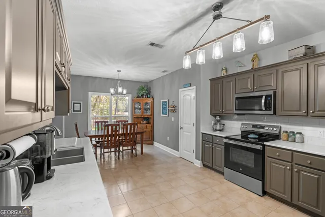 a kitchen with stainless steel appliances granite countertop a stove top oven a sink a dining table and chairs with wooden floor