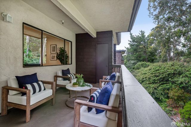 a balcony with chairs and a potted plant