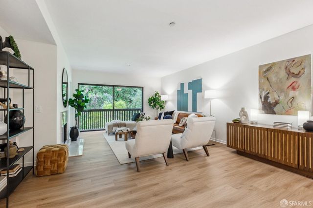a living room with furniture two window and a wooden floor