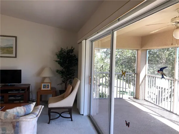 a living room with furniture a flat screen tv and a floor to ceiling window