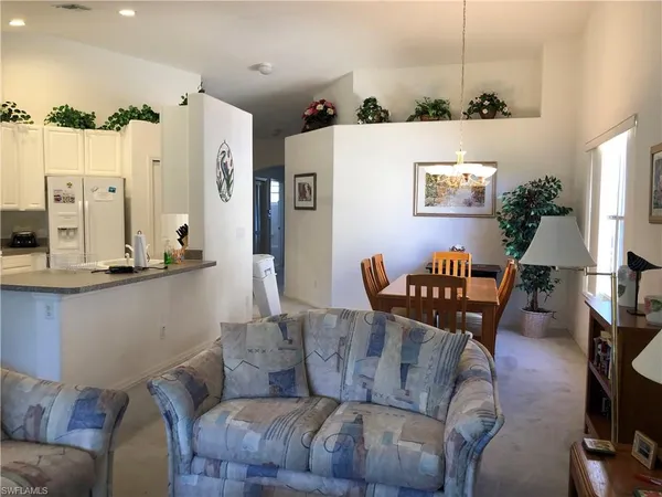 a living room with furniture kitchen view and a chandelier