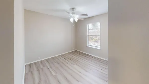 an empty room with windows and fan