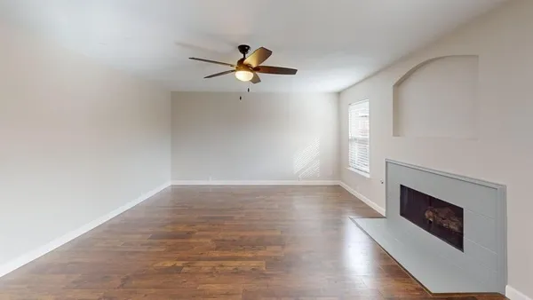 an empty room with a fireplace and wooden floor