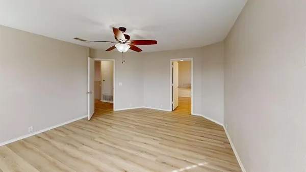 a view of empty room with wooden floor and ceiling fan