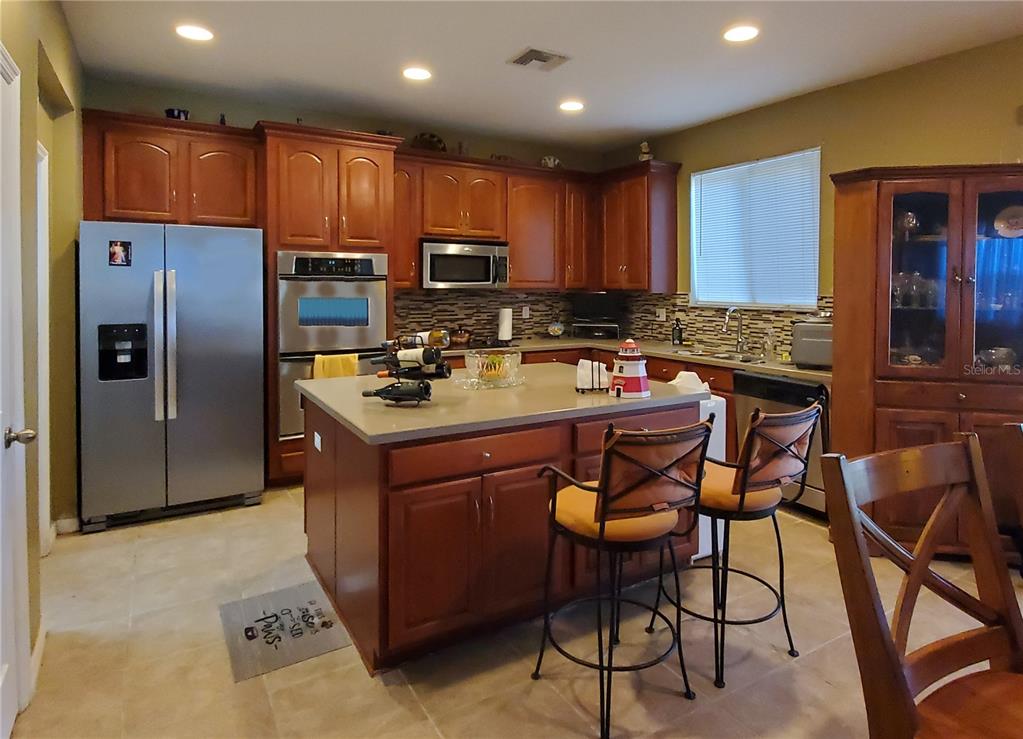 10025 Winding River Road Punta Gorda, FL 33950 - Photo 14 of 30 a kitchen with a refrigerator stove top oven dining table and chairs