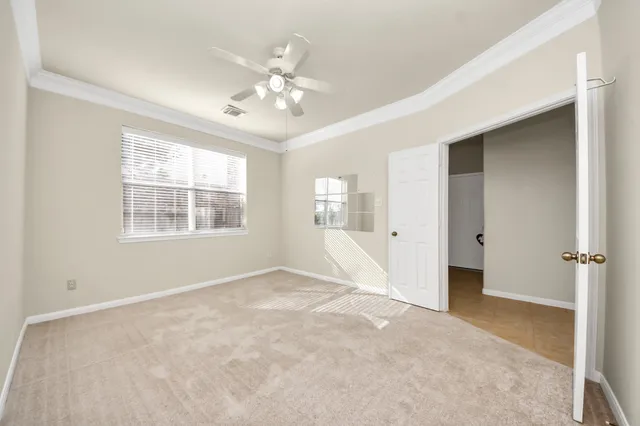 an empty room with chandelier fan and windows