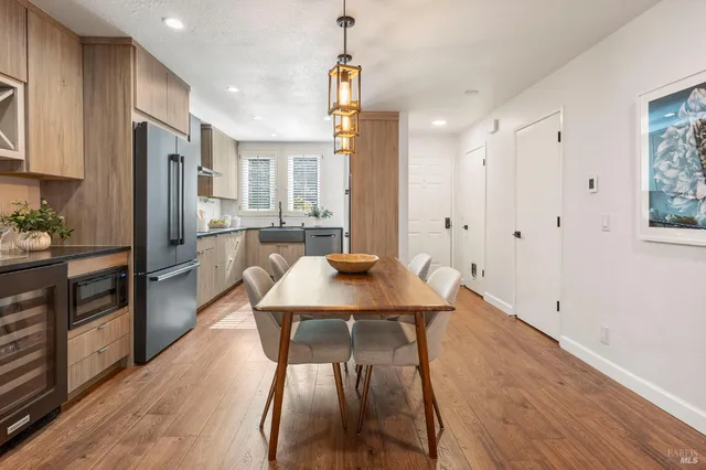 a kitchen with stainless steel appliances granite countertop a refrigerator a stove a sink dishwasher and white cabinets with wooden floor