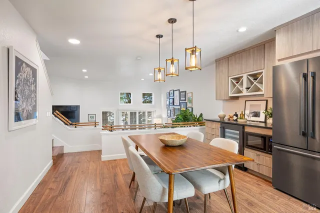 a view of a dining room and livingroom with furniture wooden floor a rug a flat screen tv a painting and a chandelier