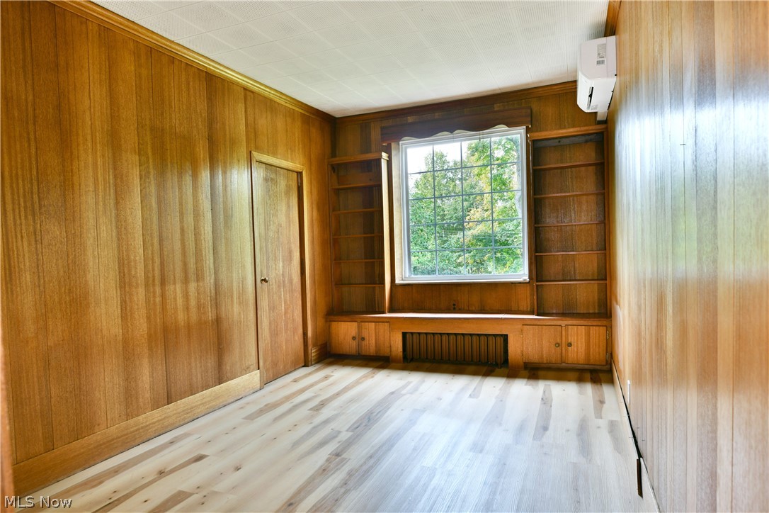 892 Yankee Run Road Masury, OH 44438 - Photo 21 of 50 Wood-paneled interior walls, natural wood-finish flooring, built-in shelving, built-in cabinetry, and an individual climate control unit