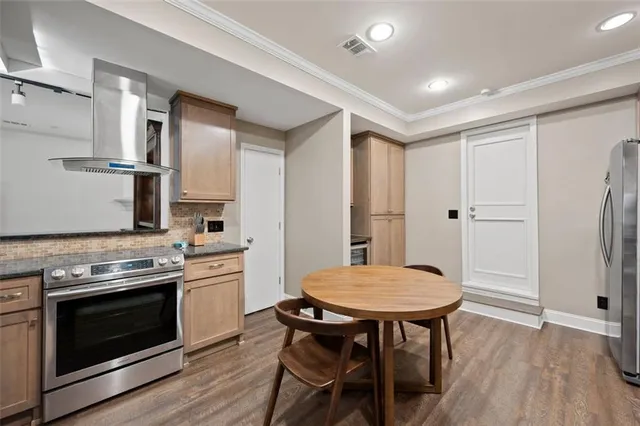 a kitchen with stainless steel appliances a stove a refrigerator and a dining table