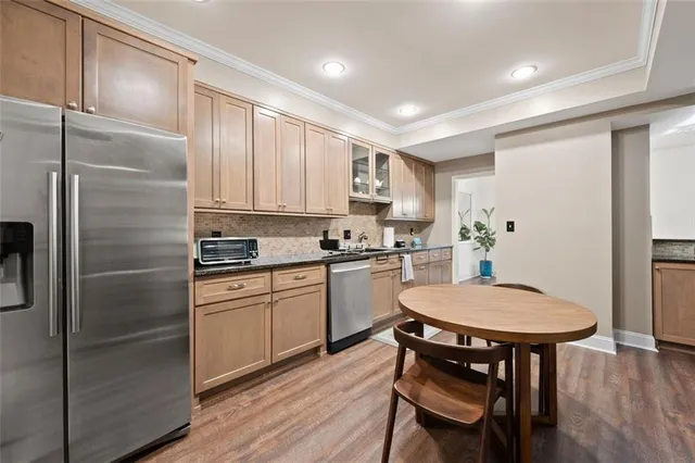 a kitchen with stainless steel appliances a dining table chairs refrigerator and sink