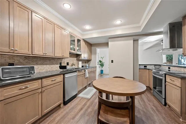 a kitchen with stainless steel appliances granite countertop a sink a stove a refrigerator a stove a dining table and chairs with wooden floor