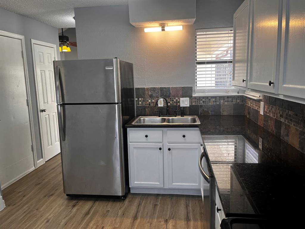 1007 Mack Place Denton, TX 76209 - Photo 8 of 37 Kitchen with stainless steel appliances, dark wood finished floors, decorative backsplash, white cabinetry, and a textured ceiling