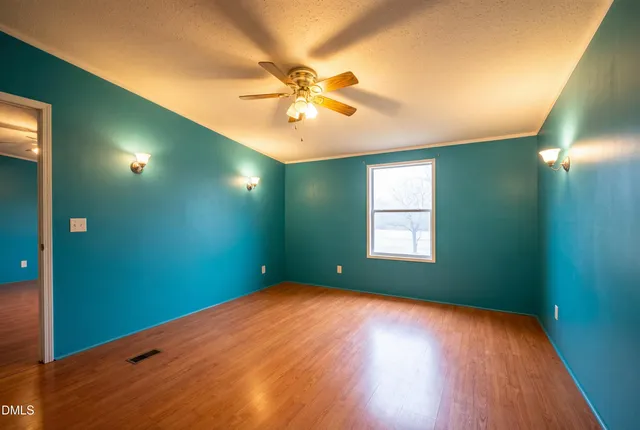 a view of an empty room with window and wooden floor