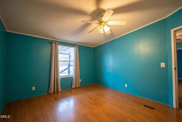 a view of an empty room with window and chandelier fan