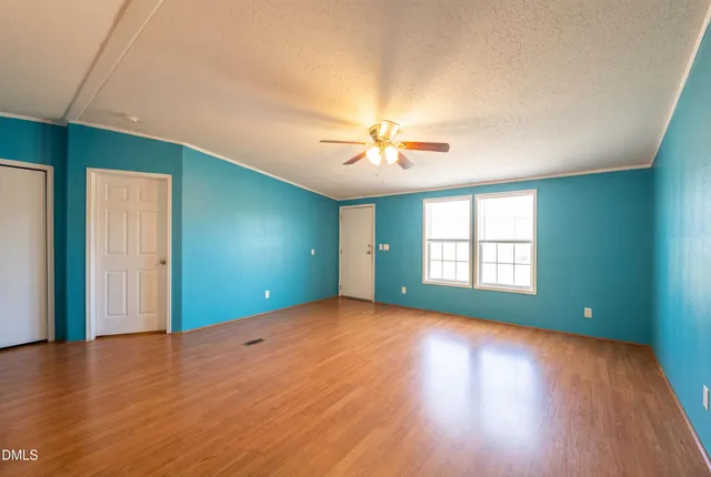 a view of an empty room with window and wooden floor