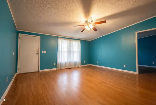 a view of an empty room with window and wooden floor