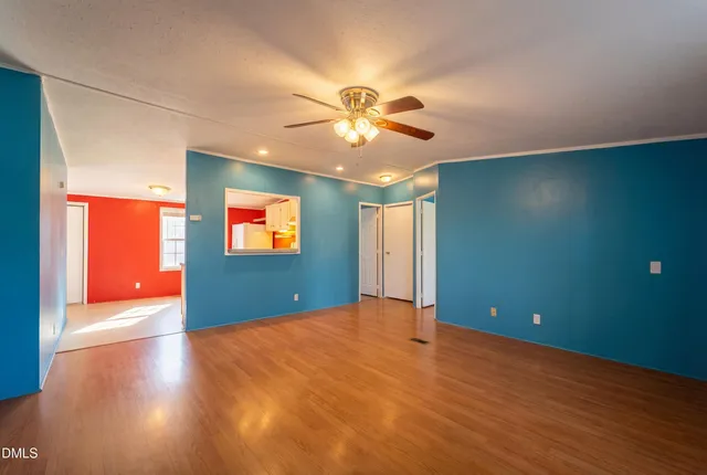 a view of an empty room with window and a kitchen