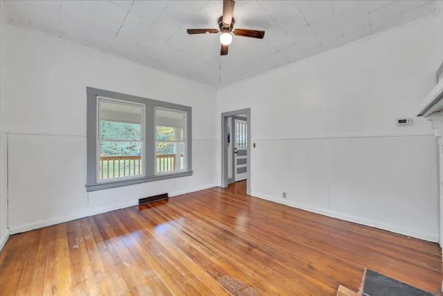 a view of an empty room with wooden floor and a window