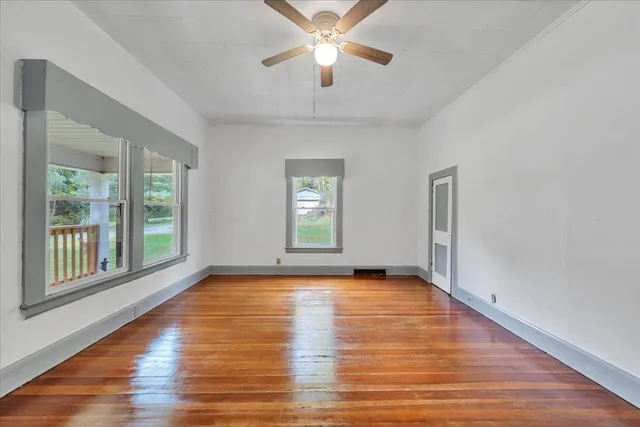 a view of an empty room with window and wooden floor