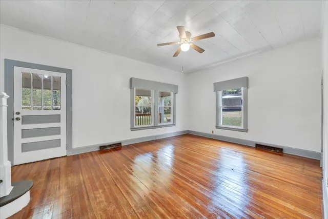 a view of an empty room with wooden floor and a window