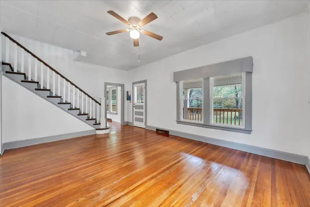 a view of an empty room with wooden floor and a chandelier
