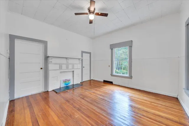 a view of empty room with wooden floor and ceiling fan