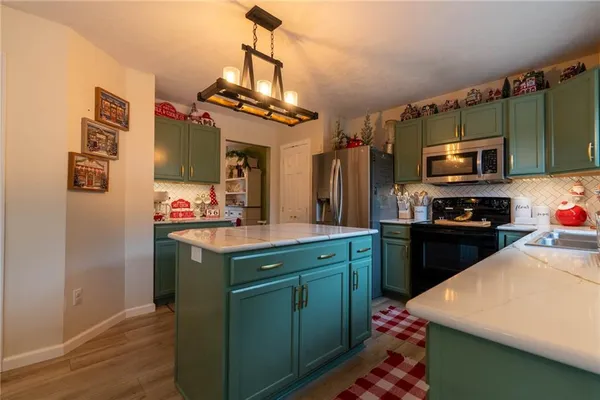a kitchen with kitchen island a sink appliances and cabinets