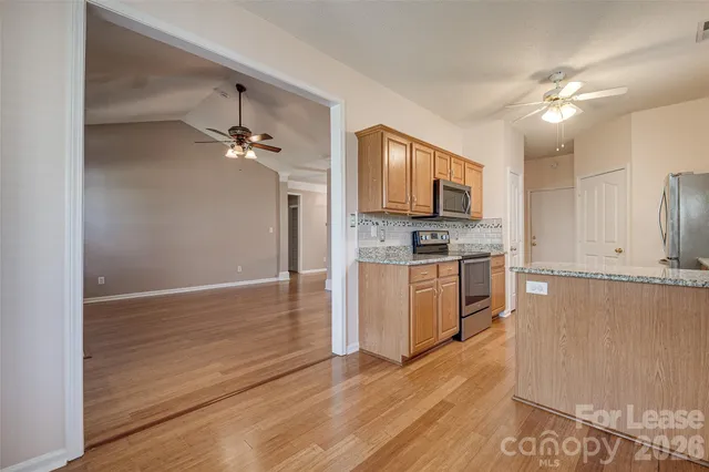 a kitchen with stainless steel appliances granite countertop a stove a sink dishwasher and a refrigerator with wooden floor