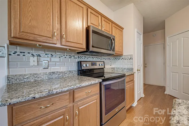 a kitchen with granite countertop cabinets stainless steel appliances and a counter space
