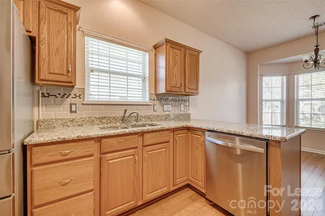 a kitchen with granite countertop cabinets stainless steel appliances a sink and a window