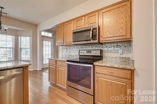 a kitchen with stainless steel appliances granite countertop a stove a sink and a microwave