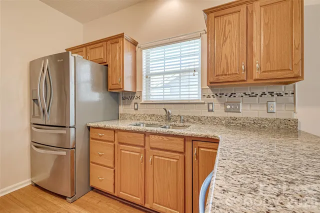 a kitchen with granite countertop a refrigerator sink and cabinets