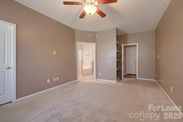 an empty room with closet and a chandelier fan
