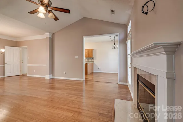 a view of an empty room with a fireplace and a ceiling fan