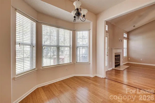 a view of an empty room with window and wooden floor