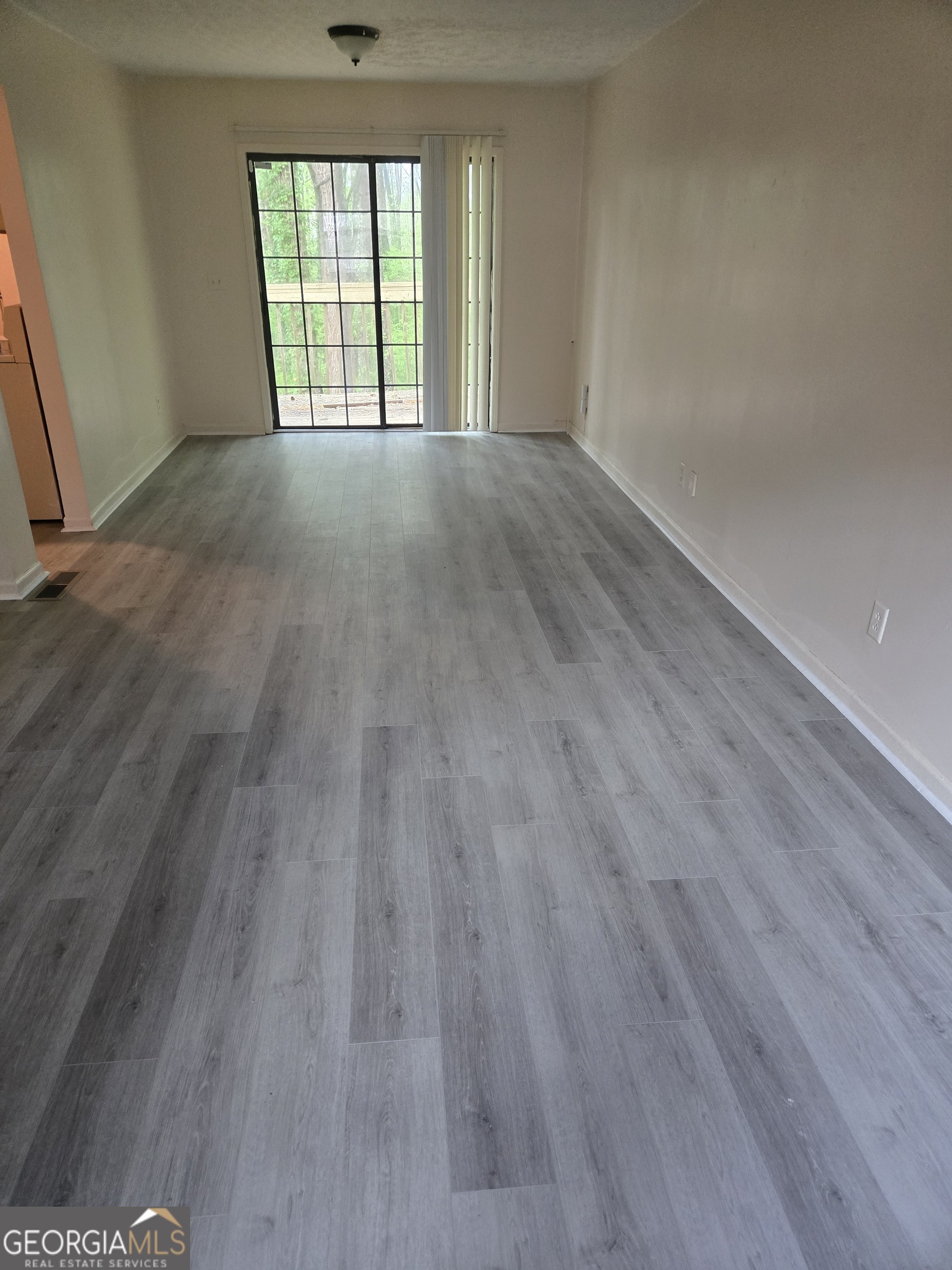 4749 Big Valley Road Stone Mountain, GA 30083 - Photo 4 of 7 a view of an empty room with wooden floor and a window