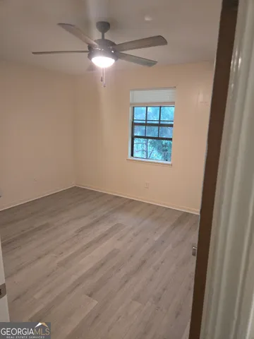 an empty room with wooden floor fan and windows