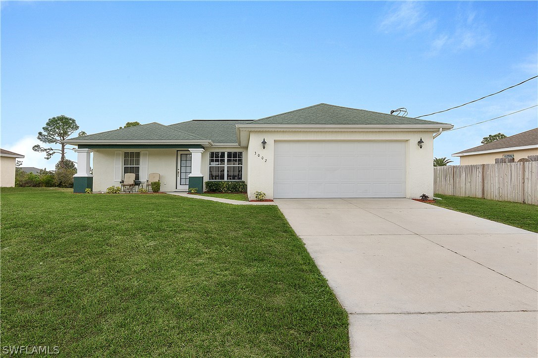 3002 52nd Street West Lehigh Acres, FL 33971 - Photo 1 of 18 a front view of a house with a garden and yard