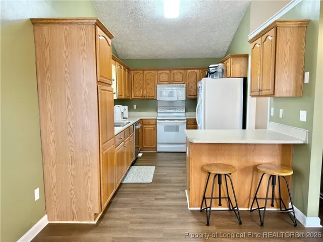 a kitchen with stainless steel appliances granite countertop a table chairs and a refrigerator