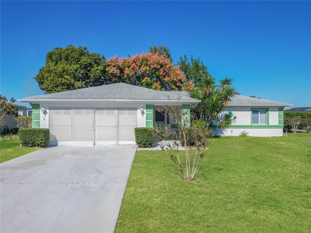 6175 Southwest 98th Loop Ocala, FL 34476 - Photo 1 of 56 a front view of a house with a yard and trees