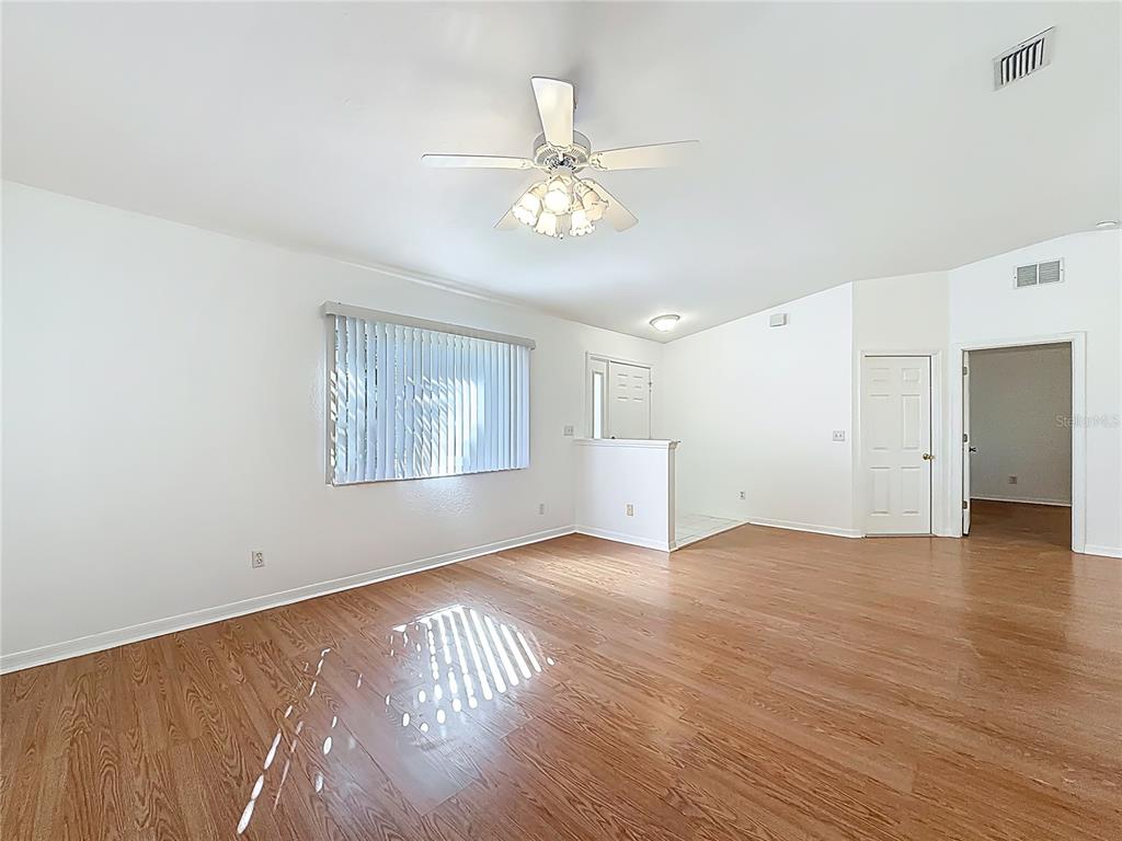 6175 Southwest 98th Loop Ocala, FL 34476 - Photo 7 of 56 an empty room with wooden floor chandelier fan and windows
