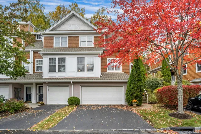 a view of a white house with large windows and a large tree