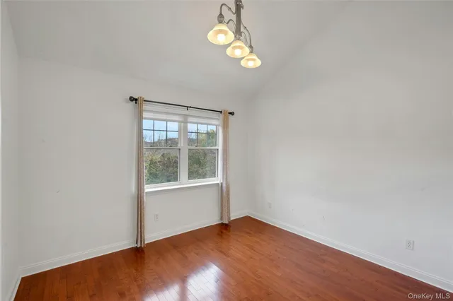 an empty room with wooden floor windows and closet