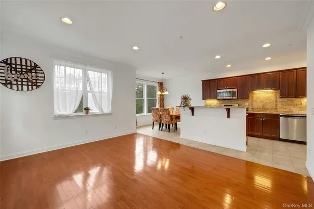 a living room with stainless steel appliances kitchen island granite countertop a stove and a wooden cabinets