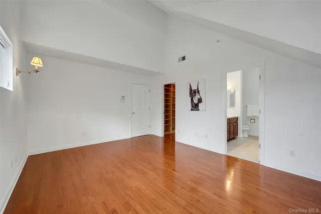 a view of an empty room with wooden floor and kitchen