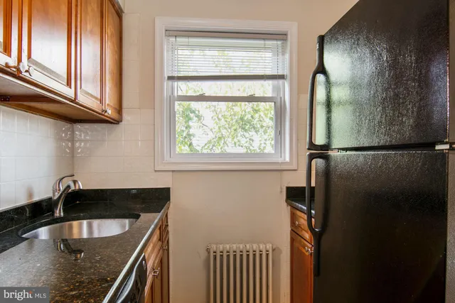 a kitchen with stainless steel appliances granite countertop a sink a refrigerator and a granite counter tops with a window