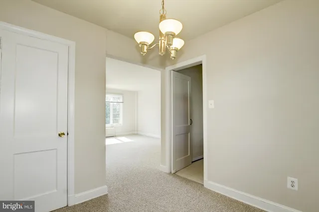 a view of a hallway with wooden floor and a chandelier