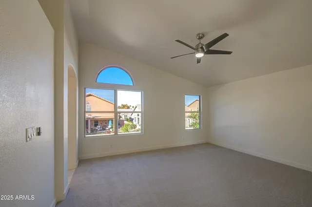 a view of an empty room with window and chandelier fan