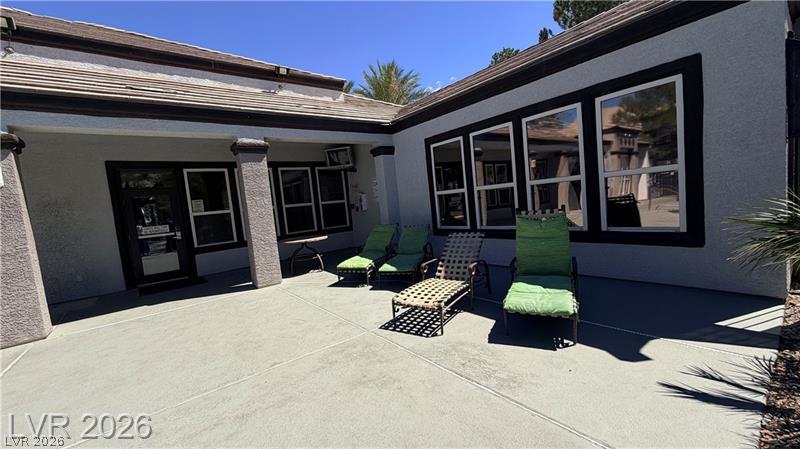 7255 West Sunset Road, Unit 2027 Las Vegas, NV 89113 - Photo 25 of 38 An inviting concrete patio area sits framed by large windows and stucco walls under clear skies.